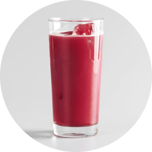 A tall, clear glass filled with a vibrant magenta or deep red-colored juice with ice cubes, set against a plain light gray background.
